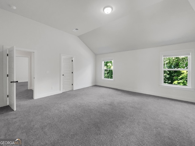 carpeted empty room with vaulted ceiling