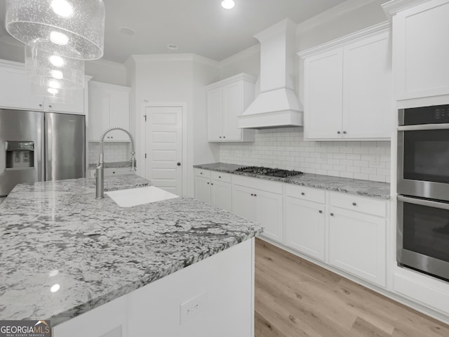 kitchen with custom range hood, light hardwood / wood-style flooring, stainless steel appliances, sink, and decorative backsplash