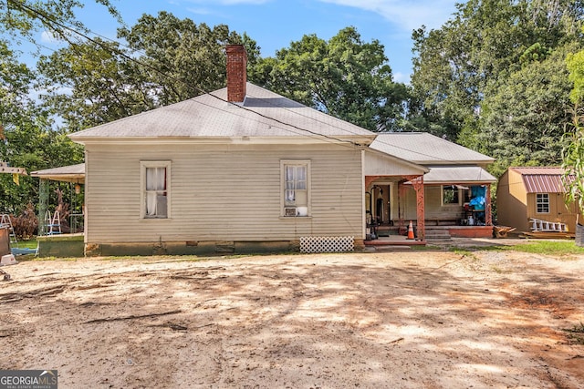 back of property featuring a porch and a storage shed