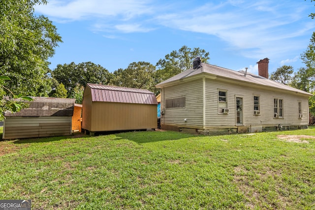 rear view of property featuring a lawn and a shed