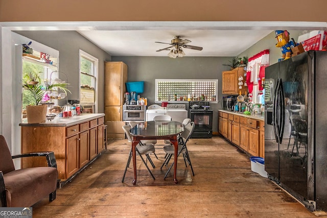 kitchen with hardwood / wood-style floors, black refrigerator with ice dispenser, washer and dryer, and ceiling fan