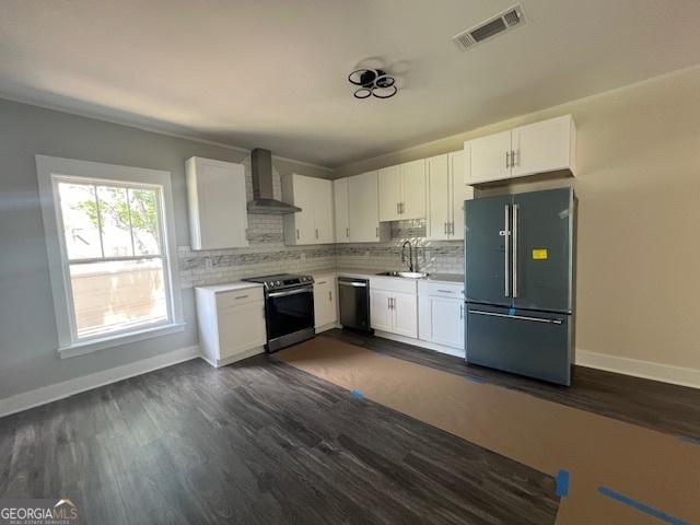 kitchen with sink, wall chimney exhaust hood, stainless steel appliances, dark hardwood / wood-style flooring, and white cabinets