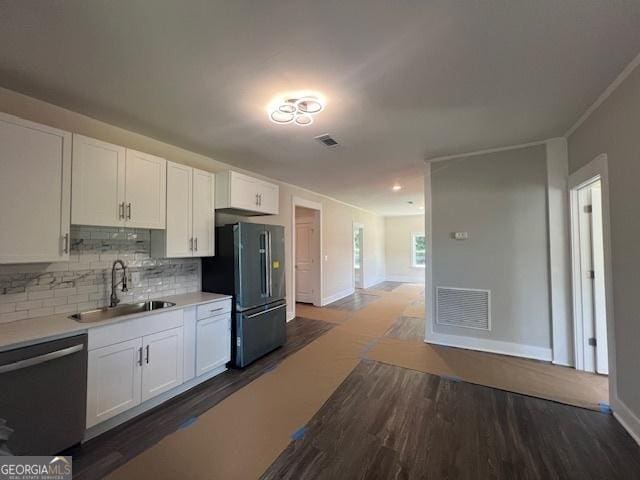 kitchen featuring dark hardwood / wood-style flooring, backsplash, stainless steel appliances, sink, and white cabinetry