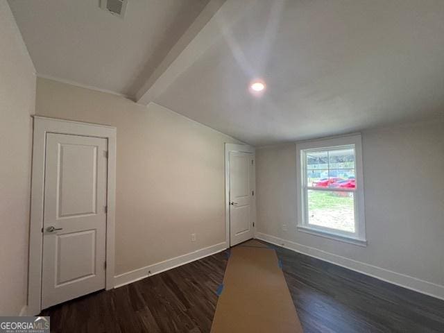 empty room featuring vaulted ceiling with beams and dark hardwood / wood-style floors