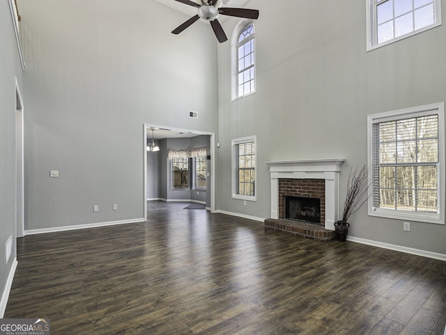1301 Crosswind Pl, Mcdonough, GA 30252 - unfurnished living room featuring ceiling fan with notable chandelier, dark wood-style flooring, a fireplace, and a healthy amount of sunlight