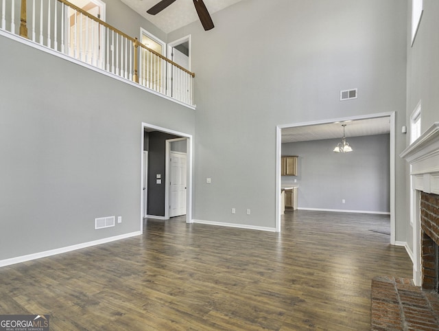 1301 Crosswind Pl, Mcdonough, GA 30252 - unfurnished living room featuring ceiling fan with notable chandelier, visible vents, dark wood-style floors, and a brick fireplace