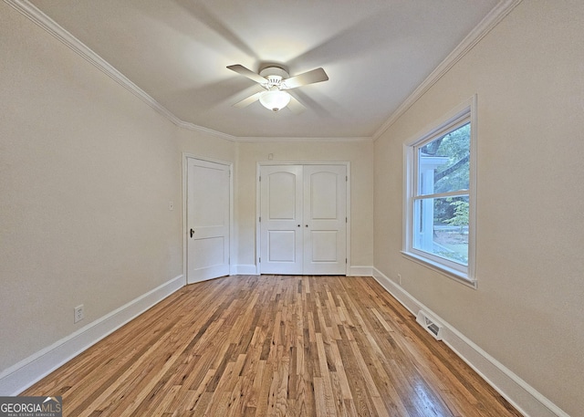 unfurnished bedroom with crown molding, ceiling fan, light wood-type flooring, and a closet