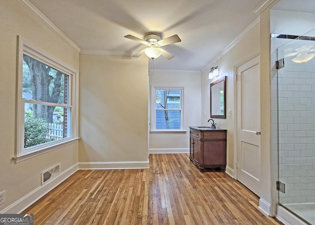 interior space featuring hardwood / wood-style floors, a shower with shower door, vanity, ornamental molding, and ceiling fan