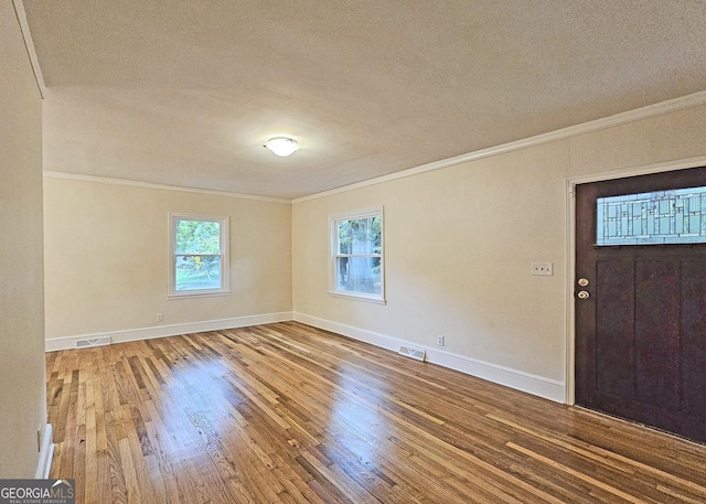 entryway featuring wood-type flooring, a wealth of natural light, and crown molding