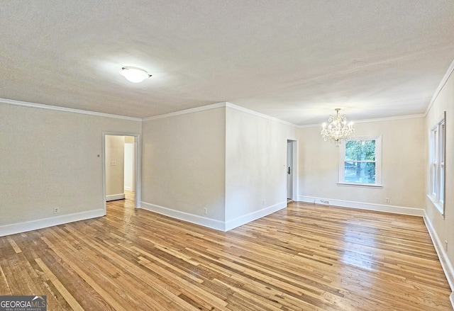 unfurnished room with ornamental molding, an inviting chandelier, and light hardwood / wood-style flooring