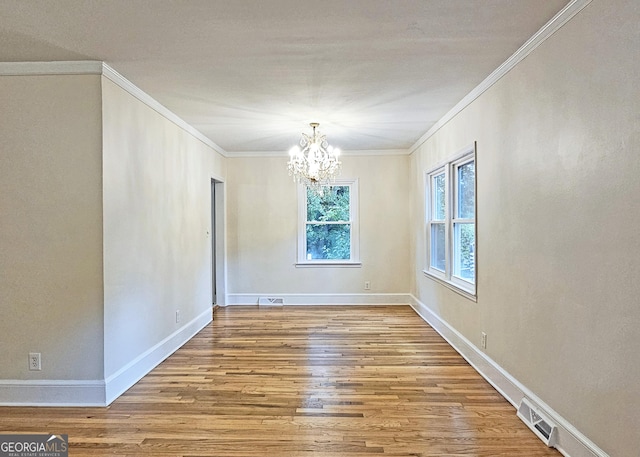 unfurnished room with hardwood / wood-style flooring, crown molding, and an inviting chandelier