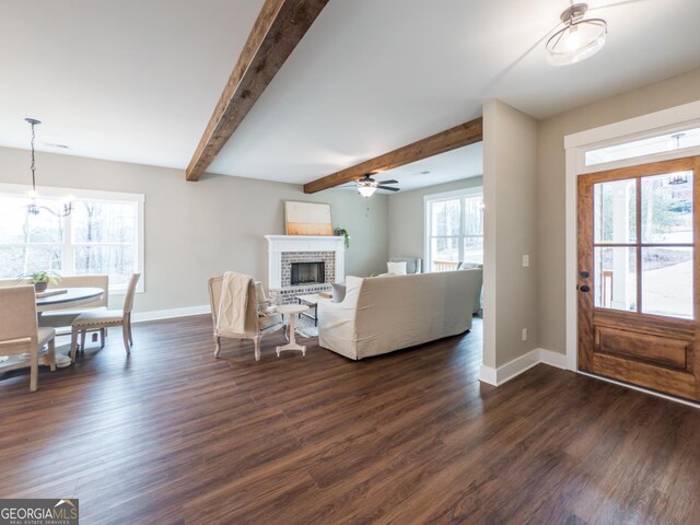 living room with dark hardwood / wood-style floors, ceiling fan with notable chandelier, and beam ceiling