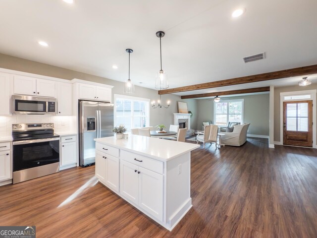 kitchen with appliances with stainless steel finishes, sink, white cabinets, and decorative light fixtures