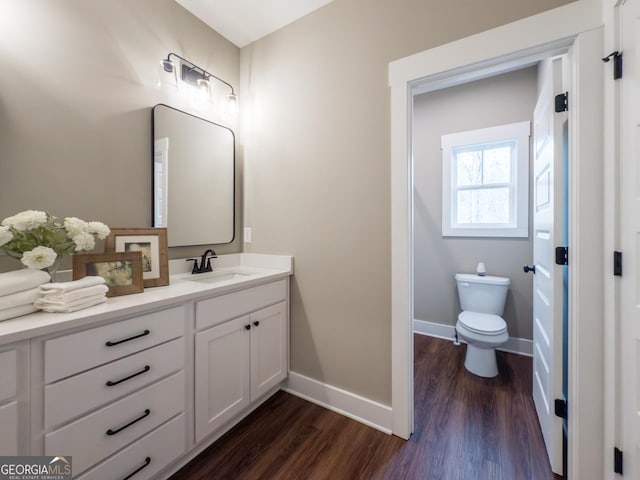 bathroom featuring wood-type flooring, toilet, and vanity