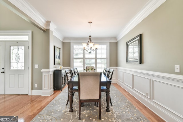 dining area with an inviting chandelier, crown molding, and light hardwood / wood-style flooring