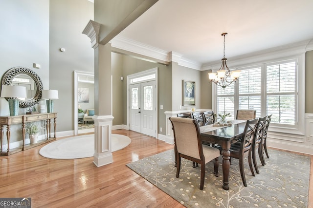 dining area with a chandelier, light hardwood / wood-style floors, ornamental molding, and decorative columns