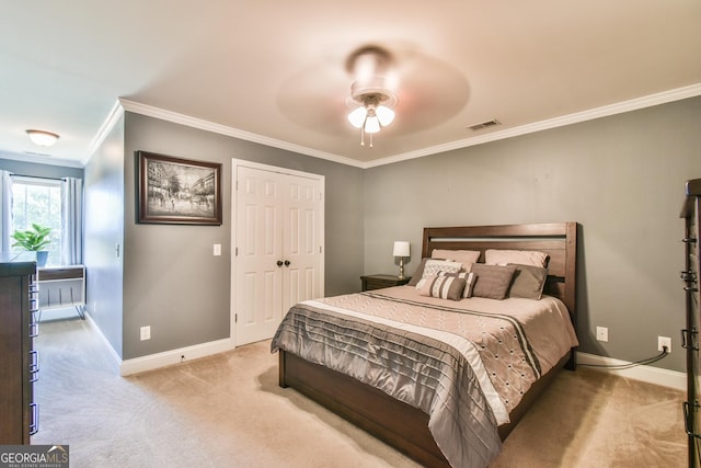 carpeted bedroom with ceiling fan, crown molding, and a closet