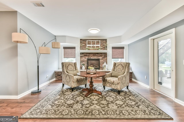 sitting room featuring wood-type flooring and a stone fireplace