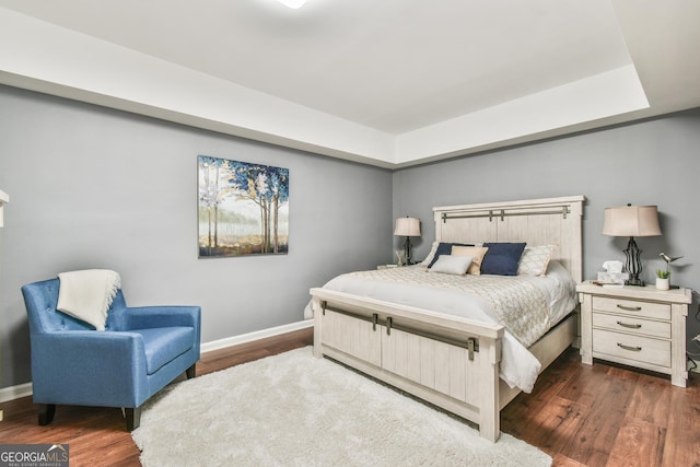 bedroom featuring dark hardwood / wood-style floors and a raised ceiling