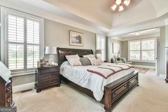 carpeted bedroom with a tray ceiling, ceiling fan, and crown molding