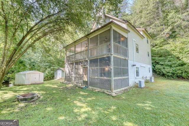 view of side of home with a shed, central AC, a lawn, and an outdoor fire pit