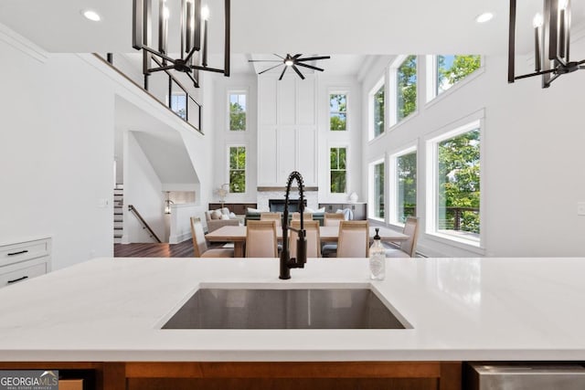 kitchen featuring hardwood / wood-style flooring, sink, pendant lighting, and ceiling fan with notable chandelier