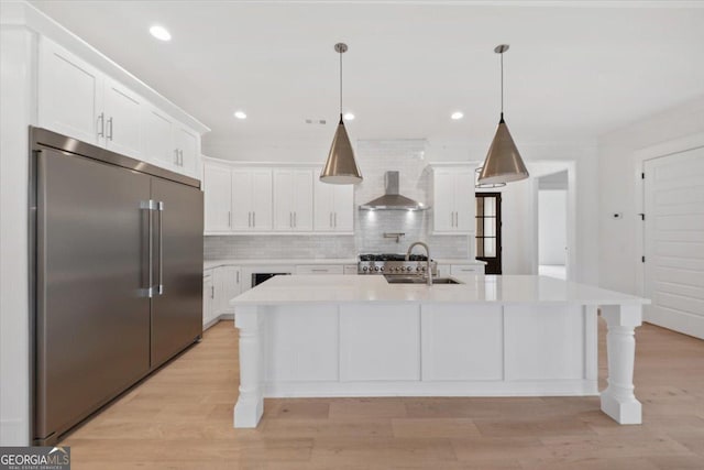 100 Tuxedo Cir, Forsyth, GA 31029 - kitchen with built in fridge, wall chimney range hood, light countertops, white cabinets, and tasteful backsplash