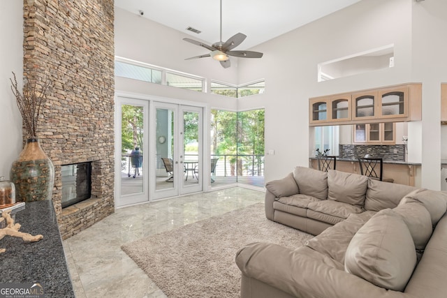 living room with a high ceiling, ceiling fan, and a fireplace