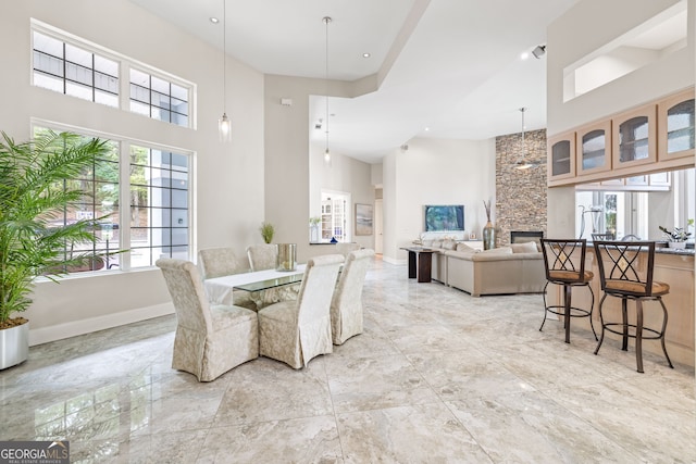 dining area with a stone fireplace and a high ceiling