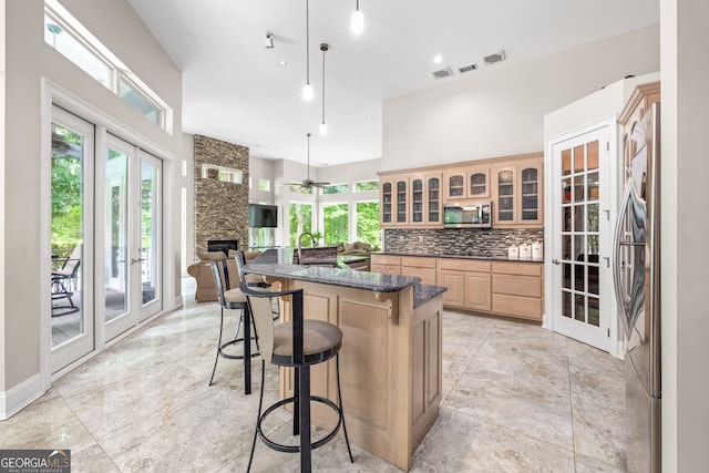 kitchen with a breakfast bar, stainless steel appliances, tasteful backsplash, decorative light fixtures, and french doors