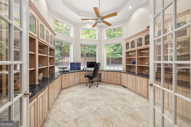 home office featuring built in desk, ornamental molding, a tray ceiling, ceiling fan, and a high ceiling