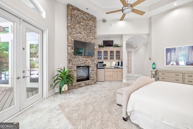 bedroom featuring a high ceiling, a stone fireplace, access to outside, and french doors