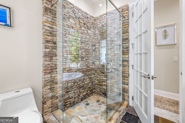 bathroom featuring toilet and a shower with door