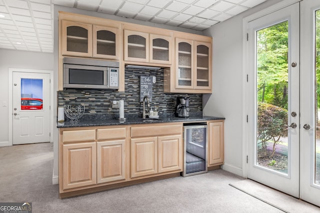 kitchen with decorative backsplash, light brown cabinetry, and dark stone counters