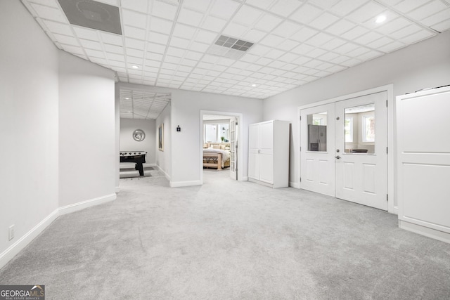 interior space featuring a drop ceiling, light colored carpet, and a healthy amount of sunlight