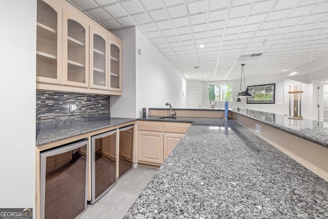 kitchen featuring tasteful backsplash, sink, dark stone countertops, beverage cooler, and light brown cabinets