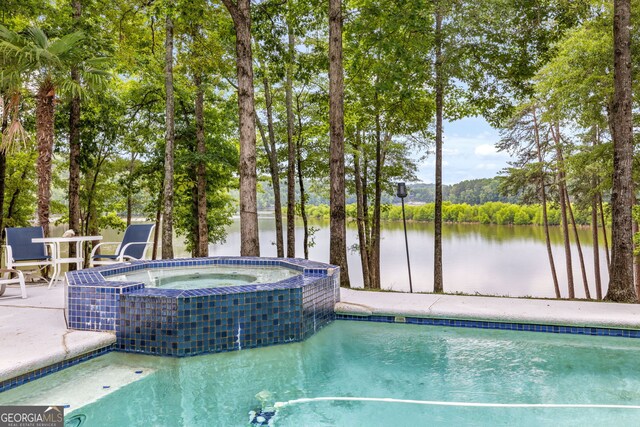 view of pool with an in ground hot tub and a water view