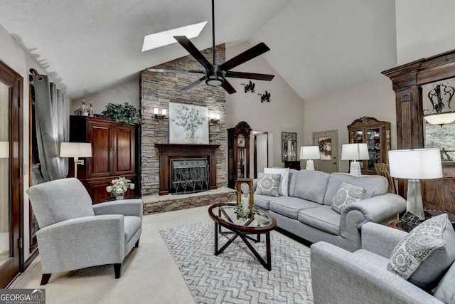 carpeted living room with ceiling fan, a fireplace, high vaulted ceiling, and a skylight