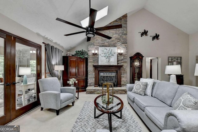 living room featuring a stone fireplace, ceiling fan, high vaulted ceiling, and light carpet