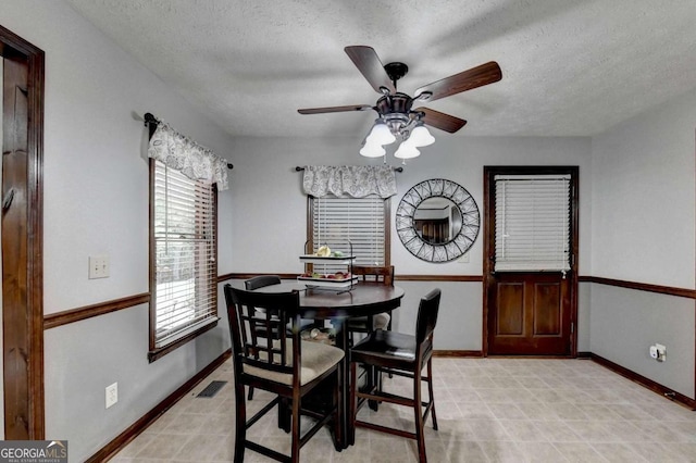 dining area featuring ceiling fan and a textured ceiling