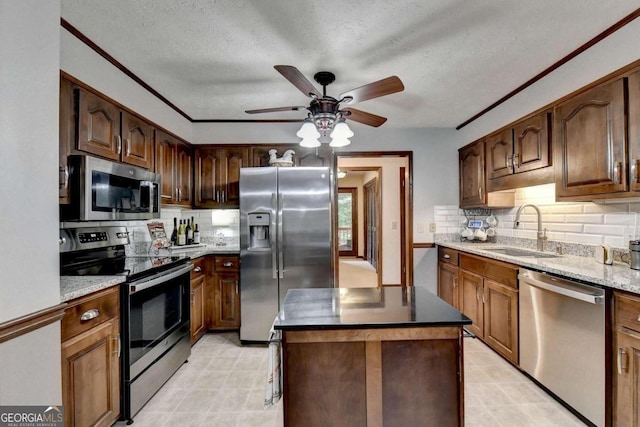 kitchen featuring sink, a textured ceiling, decorative backsplash, a kitchen island, and appliances with stainless steel finishes