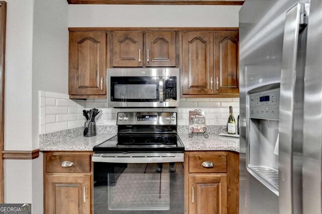 kitchen with light stone countertops, appliances with stainless steel finishes, and tasteful backsplash