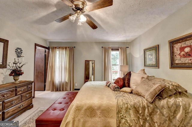 carpeted bedroom with ceiling fan and a textured ceiling