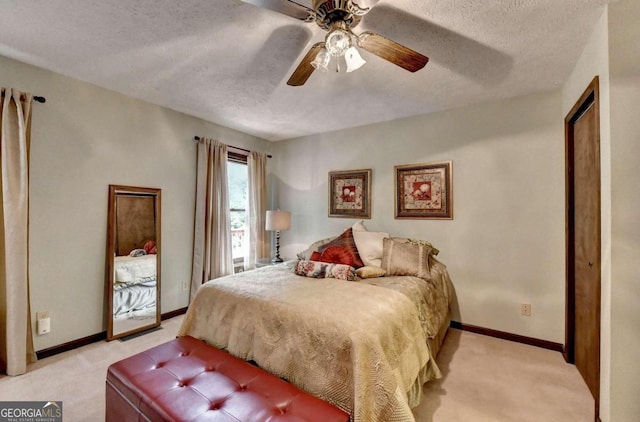 bedroom with ceiling fan, light colored carpet, and a textured ceiling