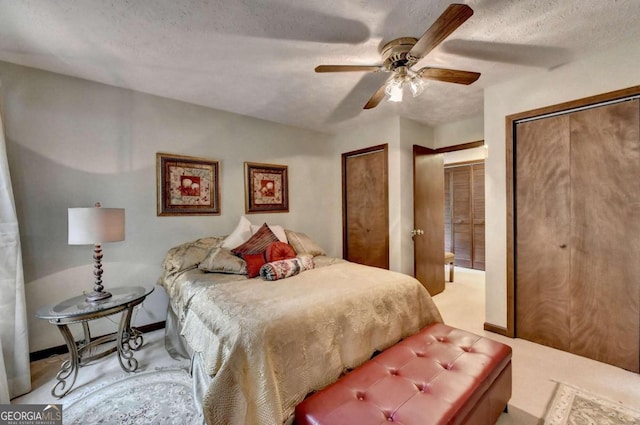 carpeted bedroom featuring multiple closets, ceiling fan, and a textured ceiling