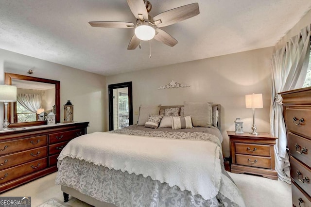 bedroom with ceiling fan, light colored carpet, and a textured ceiling