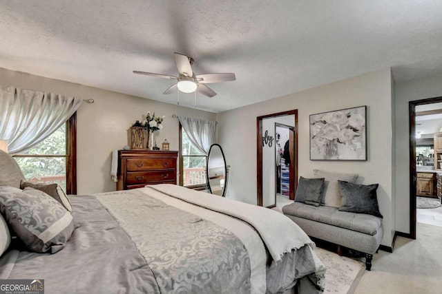 bedroom with multiple windows, a textured ceiling, light colored carpet, and ceiling fan