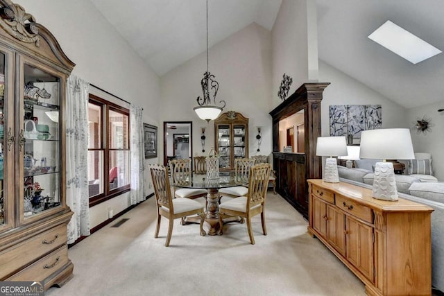 carpeted dining room featuring high vaulted ceiling and a skylight