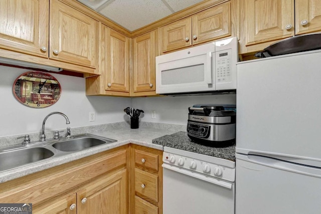 kitchen featuring white appliances, sink, and light brown cabinetry