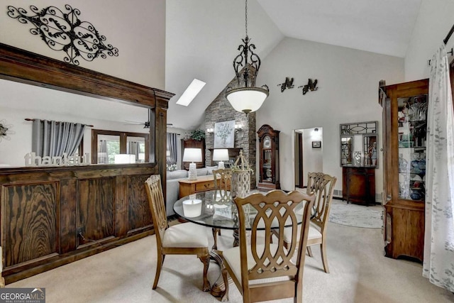 carpeted dining area with a skylight, high vaulted ceiling, and ceiling fan